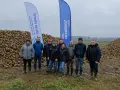 Grupa rolników pozuje na tle ogromnych hałd buraków cukrowych. Wynik tegorocznych zbiorów, pokazujący ile ton buraka cukrowego z hektara, robi wrażenie.