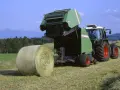 Zielone prasy rolujące małe zapotrzebowanie mocy pracują na polu, tworząc bele siana.