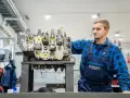 Mechanik w niebieskim kombinezonie pracuje nad budową rozdzielacza hydraulicznego w warsztacie.