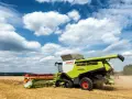 Kombajn Claas Lexion 770 pracuje na polu, zbierając zboże. To jeden z wielu znanych **marek kombajnów**.