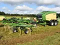 Zielony pług wahadłowy Krone COMPACK z żółtym elementem i prasą zbierającą na polu.