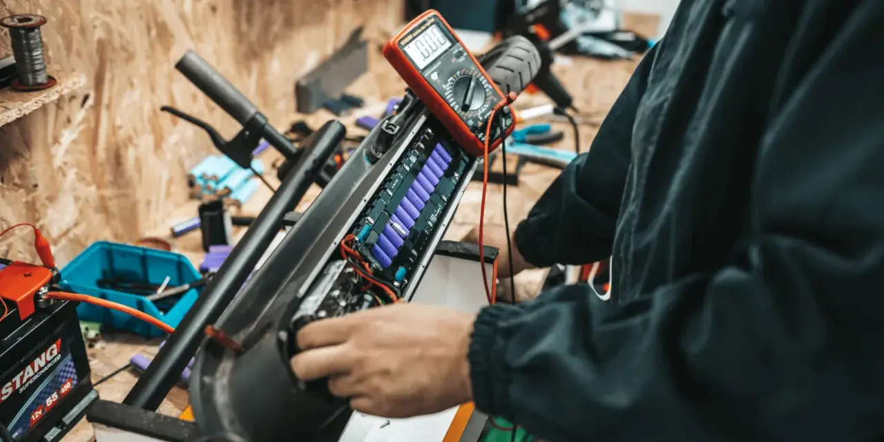 Naprawa i regeneracja akumulatorów hydraulicznych hulajnogi elektrycznej. Multimetr mierzy napięcie ogniw.