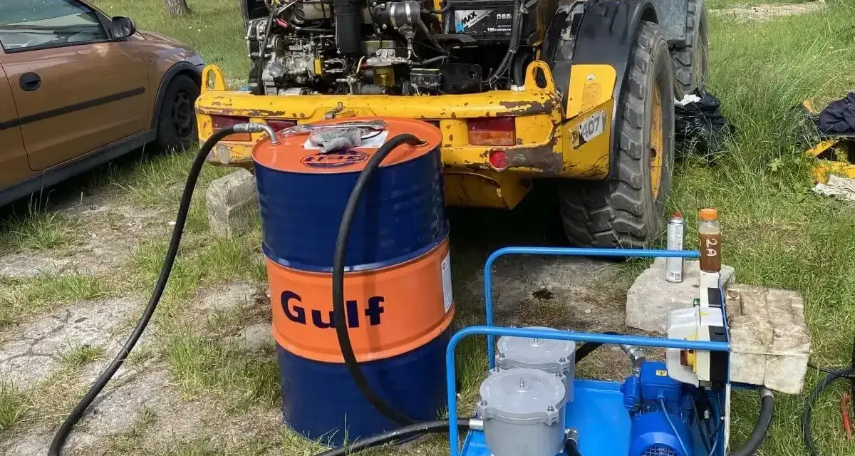 Niski poziom oleju hydraulicznego objawy: żółta maszyna budowlana, beczka Gulf, pompa do oleju.