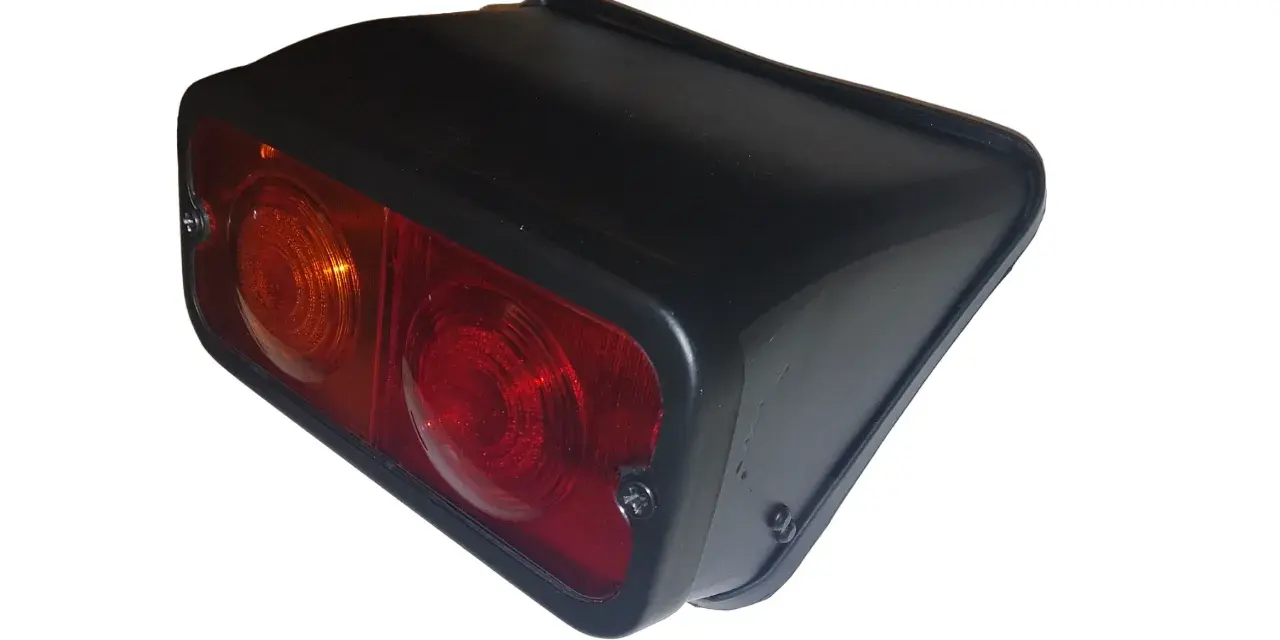 Tylna lampa Zetor z dwoma kloszami: pomarańczowym i czerwonym, w czarnej obudowie.