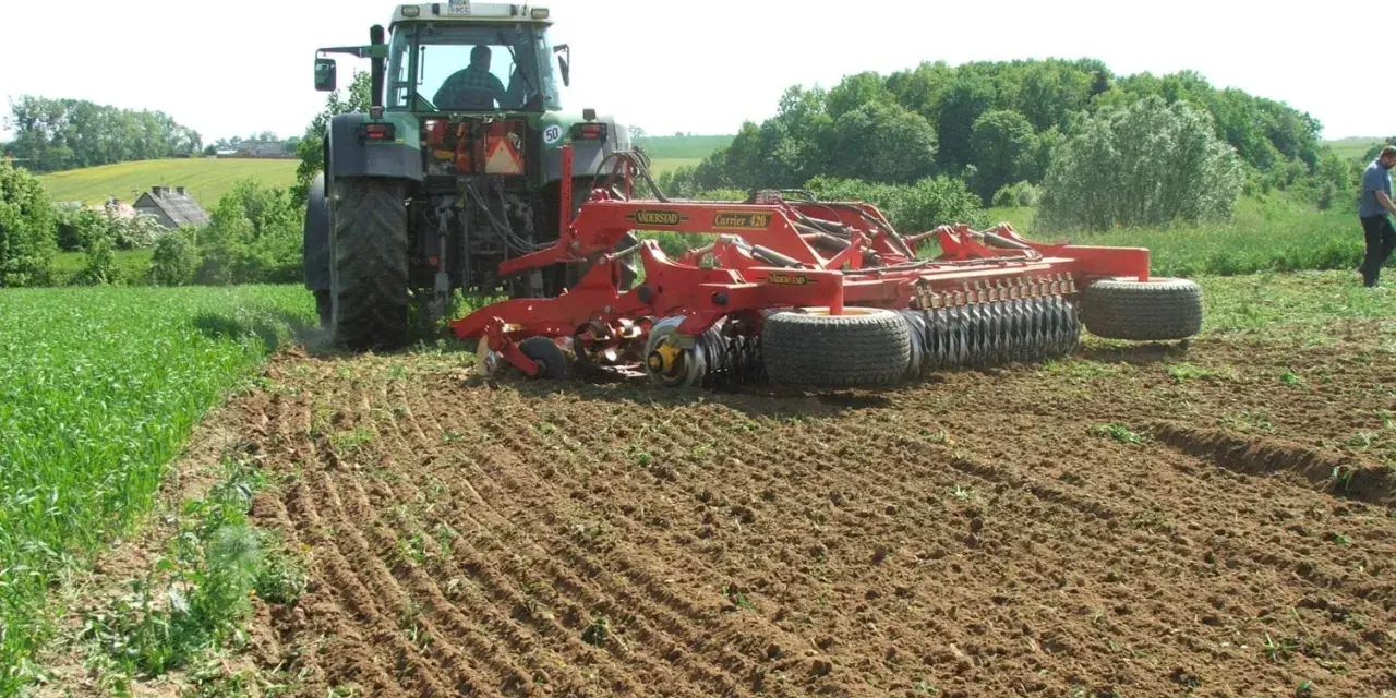 Traktor z agregatem uprawowym wykonuje podorywkę, przygotowując pole do siewu.