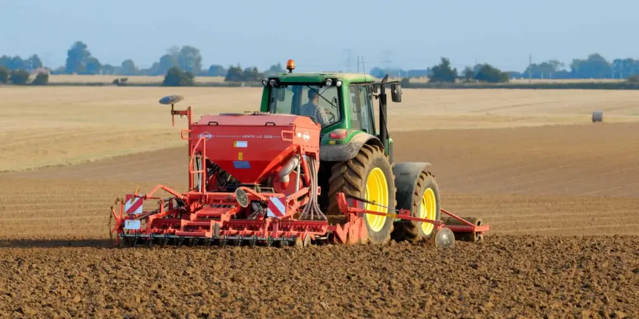 Zielony traktor z siewnikiem KUHN VENTA LC 303 precyzyjnie ustawia głębokość siewu rzepaku na przygotowanym polu.