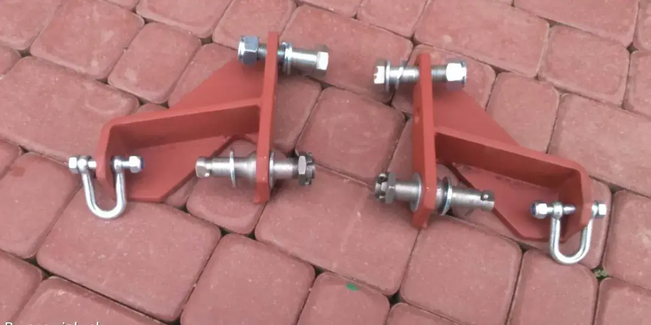 Części do t25 jak zamontować cięgno boczne podnośnika. Metalowe elementy z śrubami i nakrętkami na czerwonej kostce.