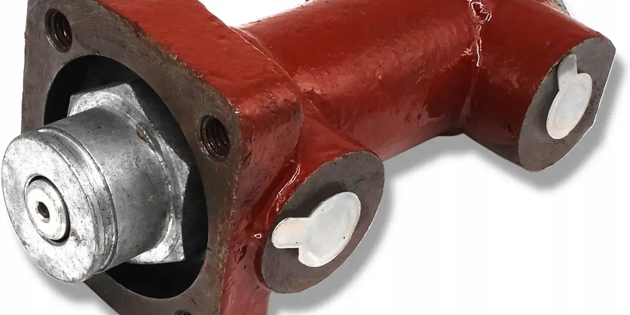 Część hamulca ciągnika Zetor: metalowy element z czerwonym korpusem i srebrnymi zaślepkami.