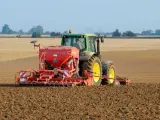 Zielony traktor z siewnikiem KUHN VENTA LC 303 precyzyjnie ustawia głębokość siewu rzepaku na przygotowanym polu.