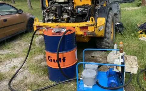 Niski poziom oleju hydraulicznego objawy: żółta maszyna budowlana, beczka Gulf, pompa do oleju.