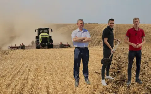 Rolnicy dyskutują o uproszczonych systemach uprawy, podczas gdy traktor orze pole.