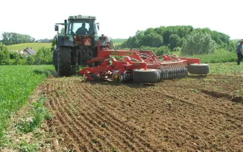 Traktor z agregatem uprawowym wykonuje podorywkę, przygotowując pole do siewu.