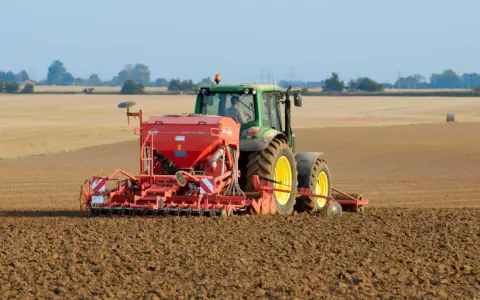 Zielony traktor z siewnikiem KUHN VENTA LC 303 precyzyjnie ustawia głębokość siewu rzepaku na przygotowanym polu.