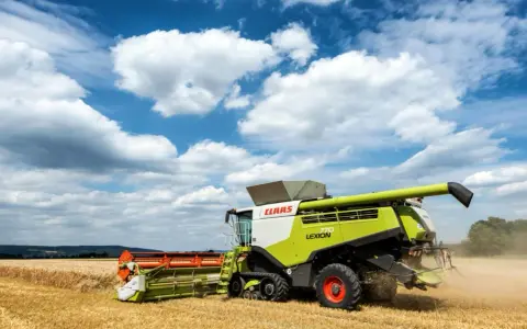 Kombajn Claas Lexion 770 pracuje na polu, zbierając zboże. To jeden z wielu znanych **marek kombajnów**.
