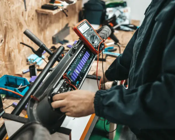 Naprawa i regeneracja akumulatorów hydraulicznych hulajnogi elektrycznej. Multimetr mierzy napięcie ogniw.