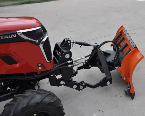 Czerwony traktor z zamontowanym z przodu pługiem śnieżnym. To jest **tuz** do pługa.