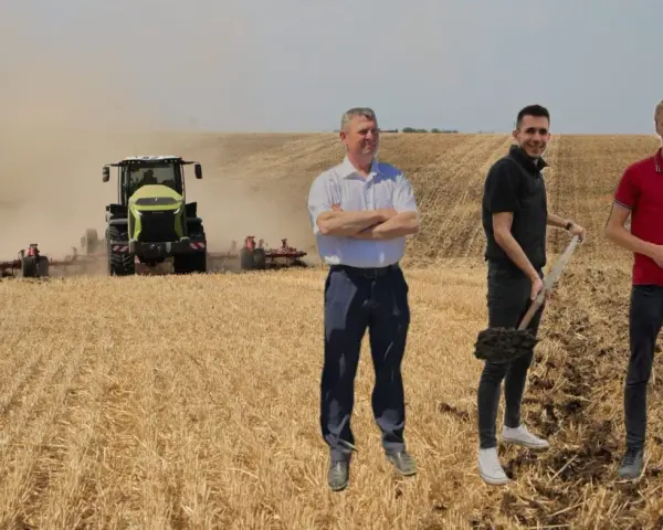 Rolnicy dyskutują o uproszczonych systemach uprawy, podczas gdy traktor orze pole.