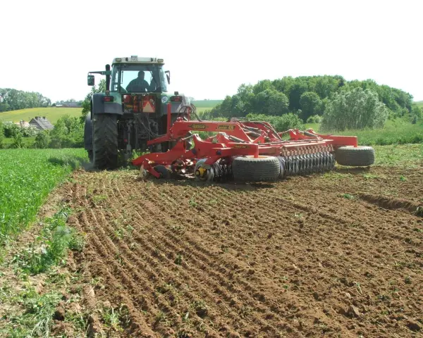 Traktor z agregatem uprawowym wykonuje podorywkę, przygotowując pole do siewu.