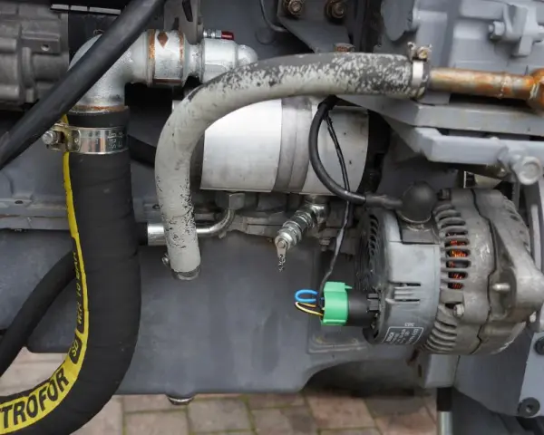 Fragment pompy hydraulicznej Ursus C-360 z przewodami i alternatorem.