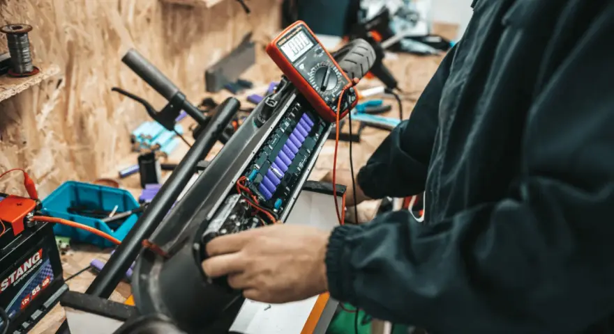 Naprawa i regeneracja akumulatorów hydraulicznych hulajnogi elektrycznej. Multimetr mierzy napięcie ogniw.