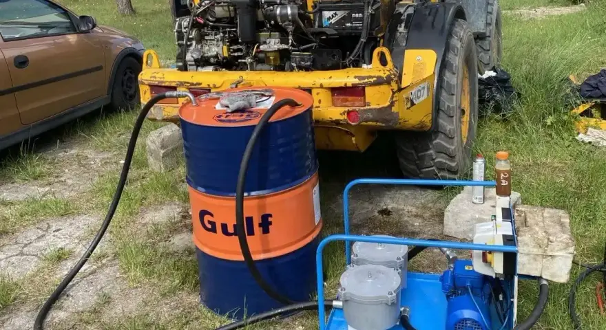 Niski poziom oleju hydraulicznego objawy: żółta maszyna budowlana, beczka Gulf, pompa do oleju.