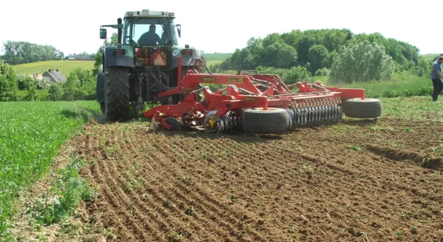 Traktor z agregatem uprawowym wykonuje podorywkę, przygotowując pole do siewu.