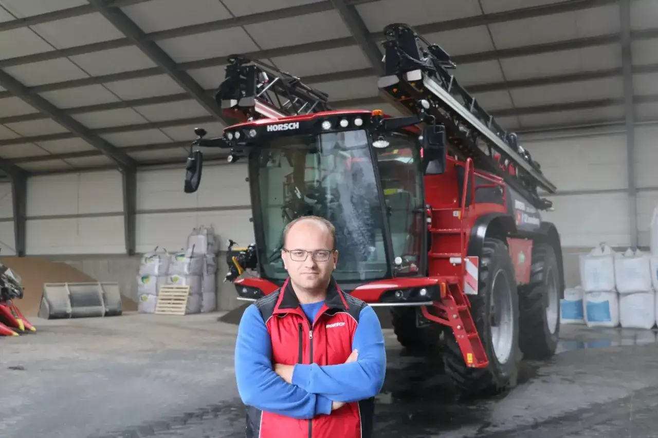 Rolnik przed nowoczesnym opryskiwaczem HORSCH. Zastanawia się, ile wody na hektar oprysku będzie potrzebne do ochrony jego plonów.