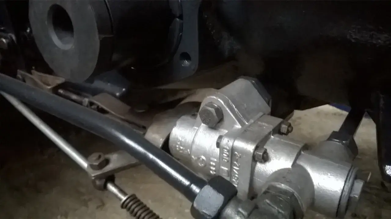 Metalowy wyrównywacz ciśnienia Zetor, element układu hydraulicznego, zamontowany na ciągniku.