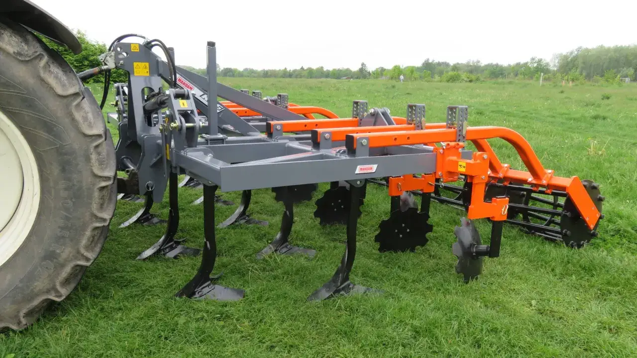 Nowy kultywator rolniczy z zębami i talerzami, gotowy do pracy na polu.